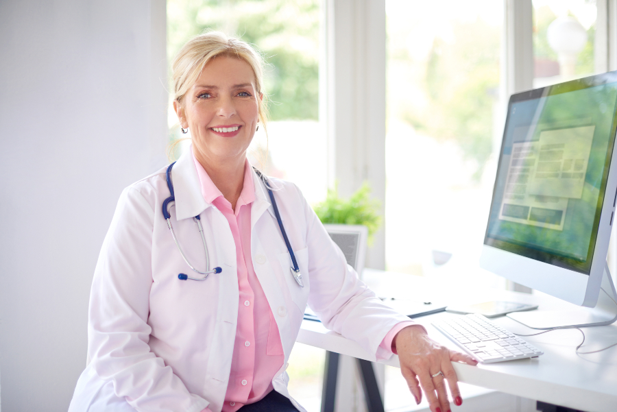 Ärztin sitzt lächelnd vor einem Computer