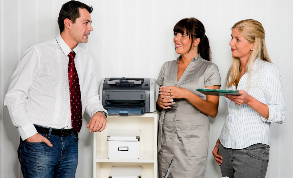 Die Gleichbehandlung aller Mitarbeiter ist ein wichtiger Grundsatz 3 Angestellte stehen neben einem Drucker