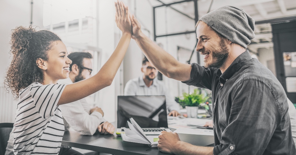 Für engagierte Mitarbeiter bieten Start-ups gute Karrierechancen Junge Leute beim "High-Five" in einem Unternehmen - Recruiting bei Start-ups