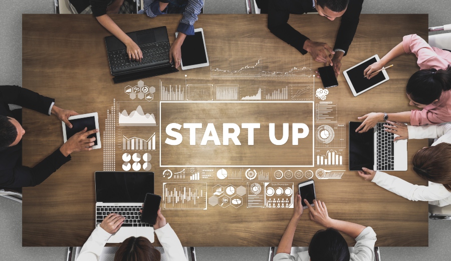 In Start-ups läuft vieles noch nicht in ganz festen Bahnen - mit all den Vor- und Nachteilen Symbolbild - Junge Leute am Tisch in einem Start-up - Recruiting für Start-ups