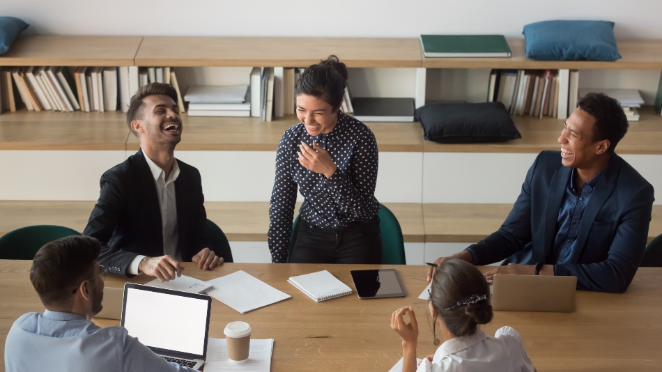 Runde junger Leute in Arbeitsumgebung unterhalten sich fröhlich - Führungsstile in Unternehmen