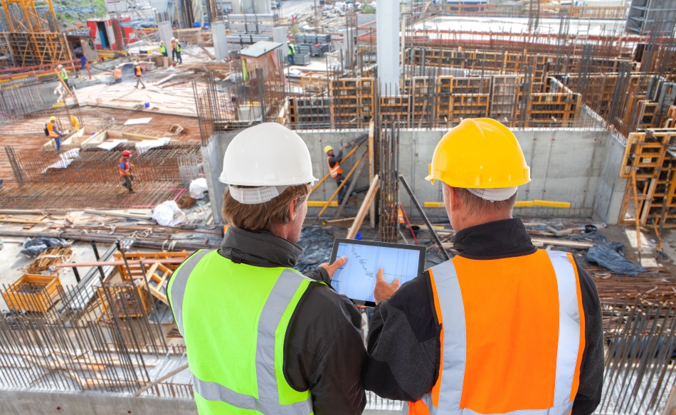 Zwei Architekten/Handwerker begutachten eine große Baustelle aus erhöter Position