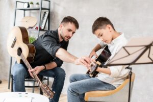 Gitarrenlehrer hilft jungem Schüler