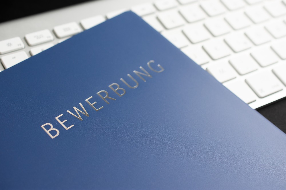 Sich aus einem bestehenden Arbeitsverhältnis heraus zu bewerben ist der Idealfall Bewerbungsmappe liegt auf Keyboard - Bewerben ohne Zeugnis