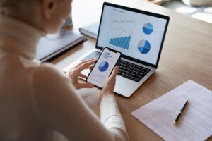 Prognosen sind ihrer Natur nach mit Unsicherheiten verbunden Jemand analysiert Unternehmenszahlen am Computer bzw. Handy - Die Umsatzplanung im Businessplan